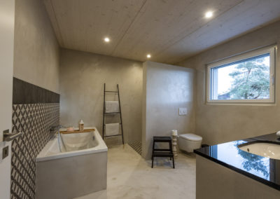 Cette image représente l'intérieur de la salle de bain d'une maison individuelle construite en ossature bois par Volery Frères SA. Les planchers sont réalisés grâce à la pose d'une dalle bois visible en plafond et blanchie.