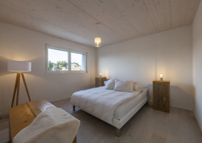 Cette image représente l'intérieur d'une maison individuelle construite en ossature bois par Volery Frères SA. Les planchers sont réalisés grâce à la pose d'une dalle bois visible en plafond et blanchie.