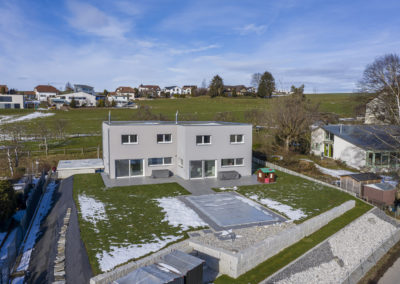 Cette image représente l'extérieur d'une maison jumelée construite en ossature bois par Volery Frères SA. L'exécution a été réalisée par préfabrication des éléments afin de permettre un montage plus rapide sur site.